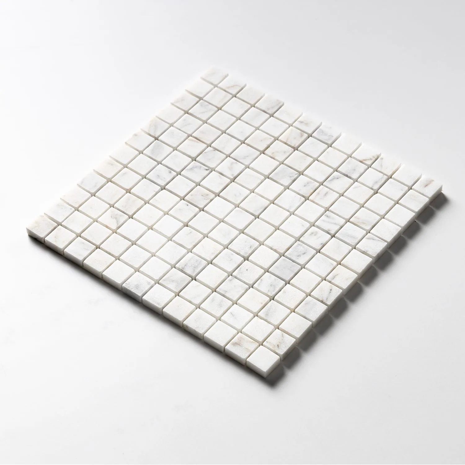 The same one-inch Calacatta Gold sheet tilted, its cut edge showing the depth of the individual squares.