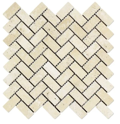 Tumbled Ivory travertine in a 1 by 2 inch herringbone, the cream chips softened at every edge with visible natural pitting.