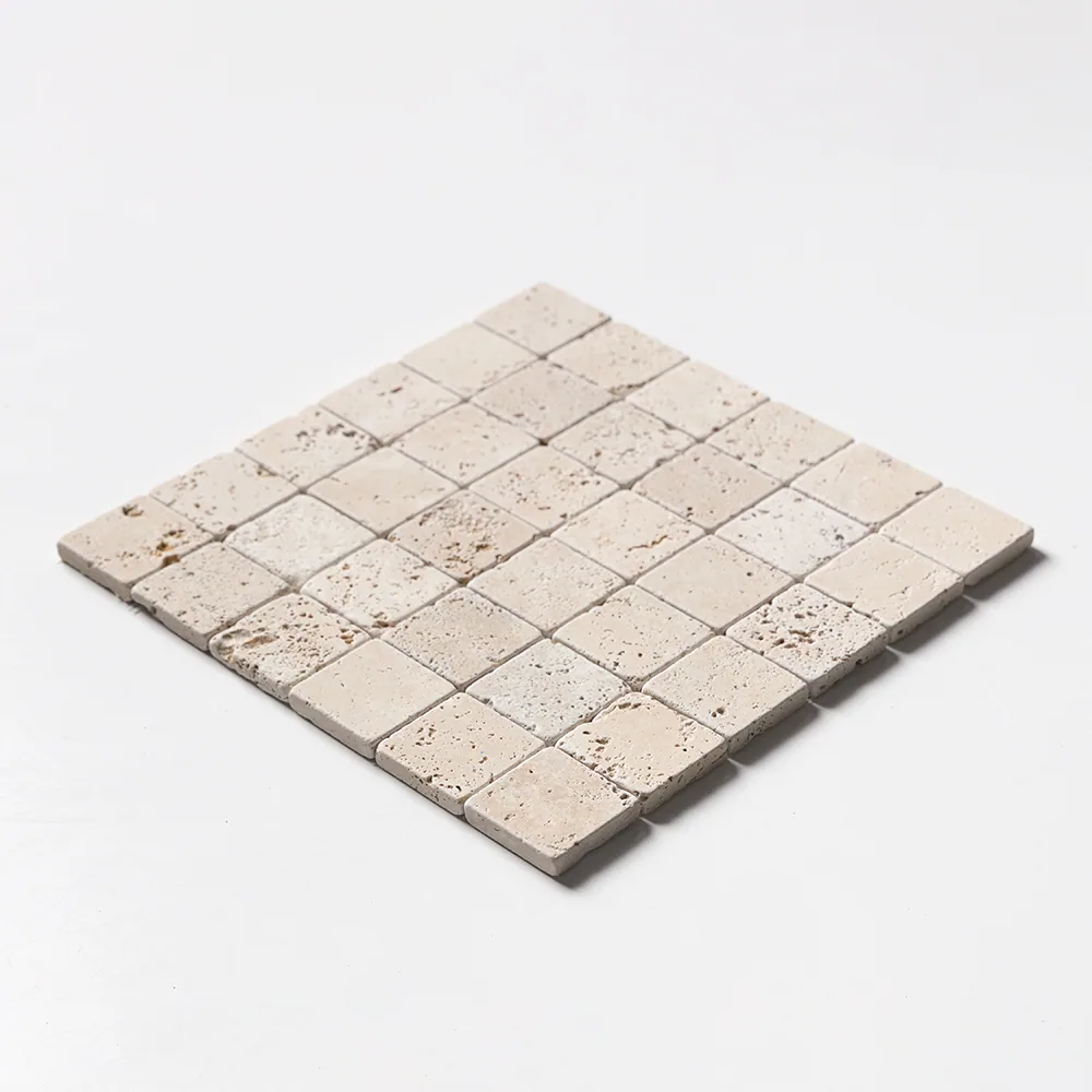 Ivory travertine mosaic of two-inch tumbled squares, the sheet angled to show its softened edges and warm cream tone.
