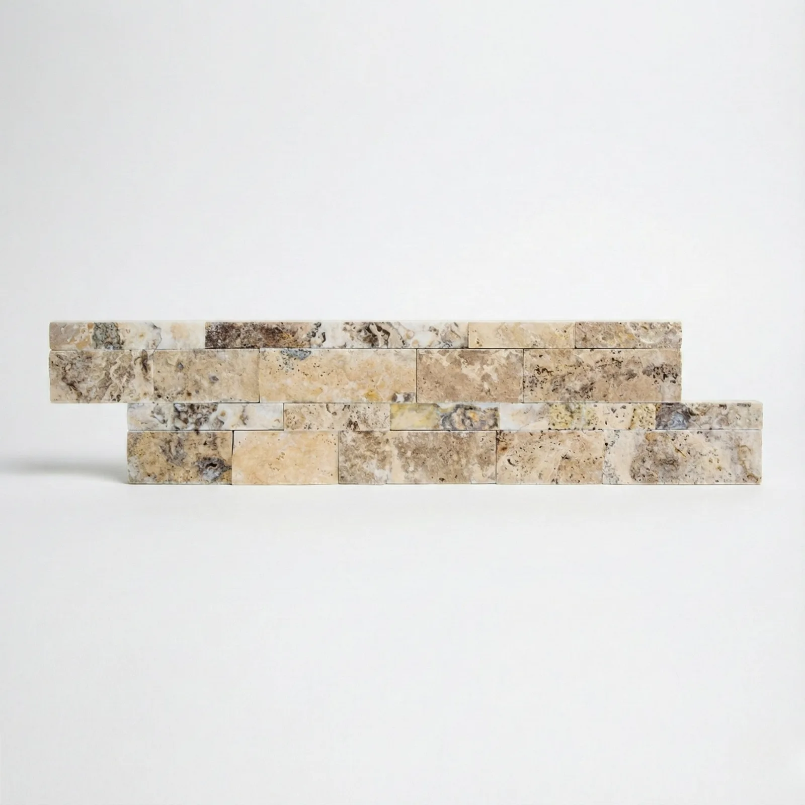 Philadelphia travertine ledger panel corner piece on a pale studio ground: split-face strips mixing cream, grey and ochre across two offset courses, with the open pitting characteristic of the stone.