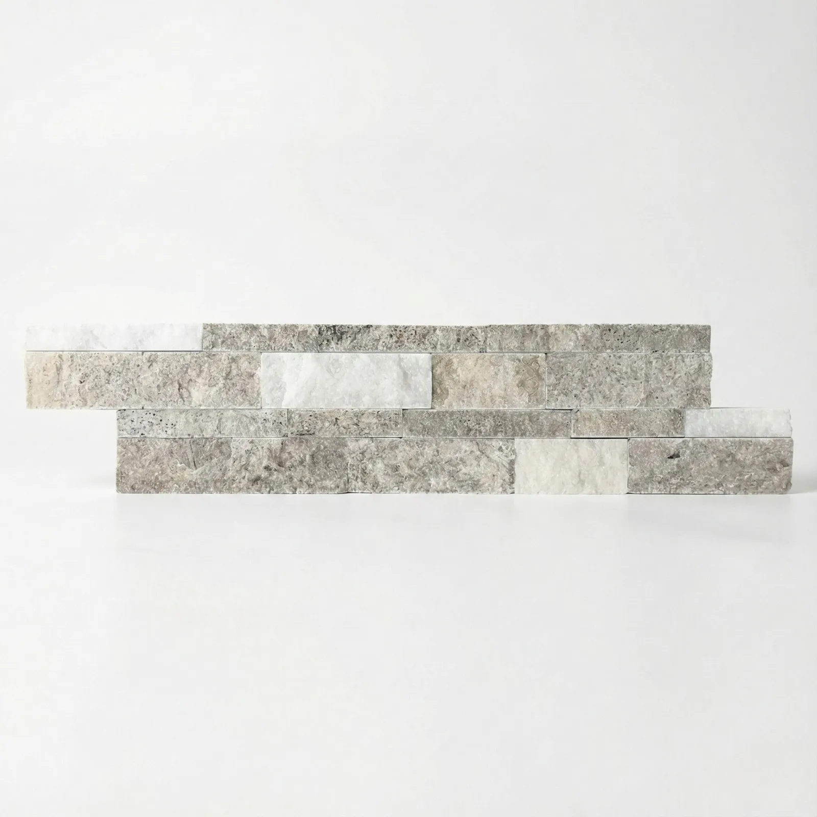 Silver White travertine ledger panel corner piece on a pale studio ground: split-face strips in cool grey banded with chalk white across two offset courses, the coolest of the travertine panels.