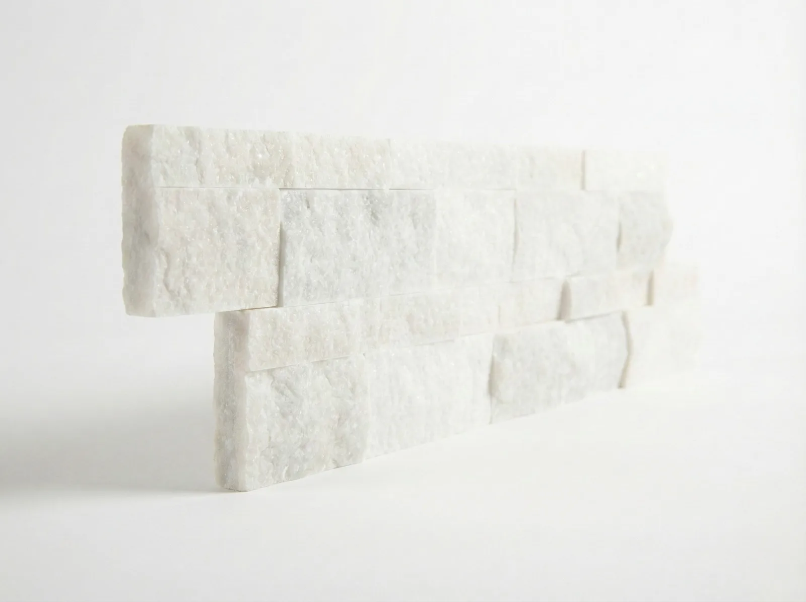 A white marble ledger panel corner piece on a studio ground, the returned end showing the panel's depth.
