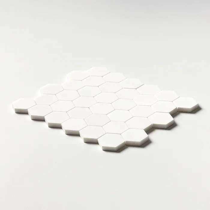 Two-inch hexagons of polished Snow White marble, uniformly bright white, the sheet tilted low against a white ground.
